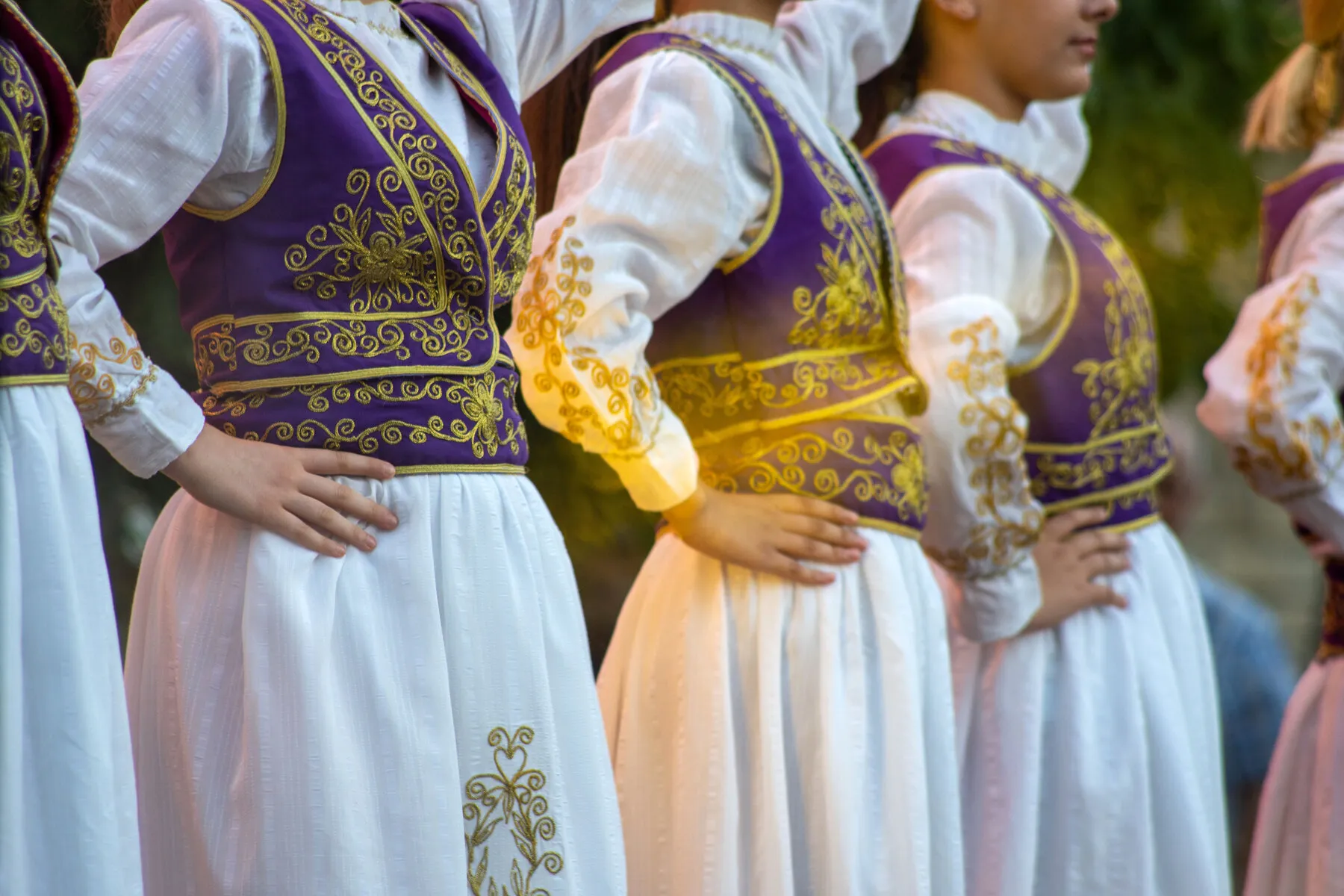 Detail of hand-embroidered Albanian folk costumes in purple, gold, and white